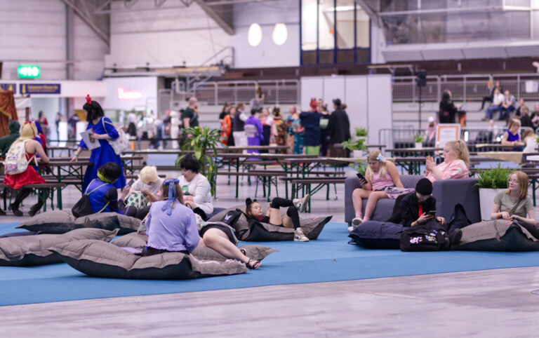 Kotae Expo 2024 hengailualueesta kuva. Etualalla harmaita säkkituoleja, joissa istuu ihmisiä. Taustalla tuoli ja penkkiryhmiä ja käveleviä nuoria ja aikuisia.